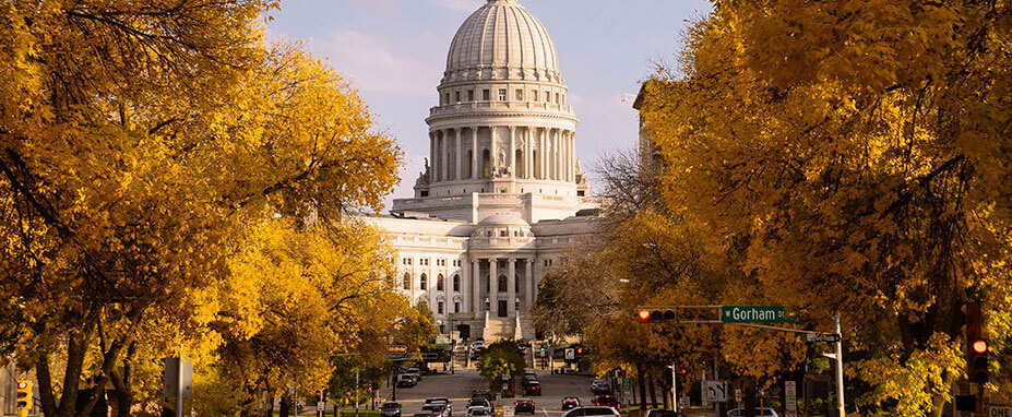 Trees in yellow and orange shades line the street leading up to the State Capitol building in Madison
