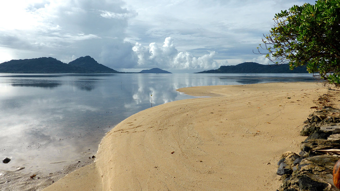 Curved sandy coastline of Micronesia seen on a cloudy day