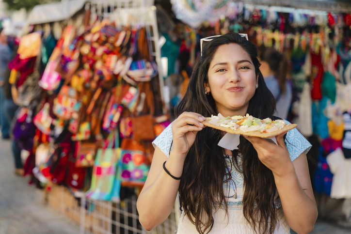 Mujer latina comiendo tlayuda en un mercado de Oaxaca.